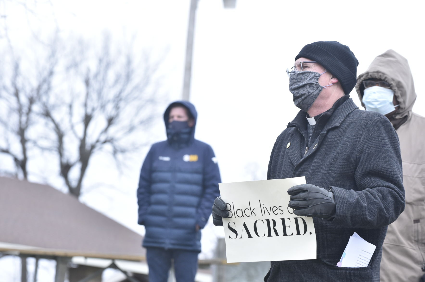 Pastor holds sign reading "Black lives are sacred"